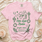 Pink t-shirt with "Her Last Rodeo" text, cowboy boots, hat, cacti, and guitar.