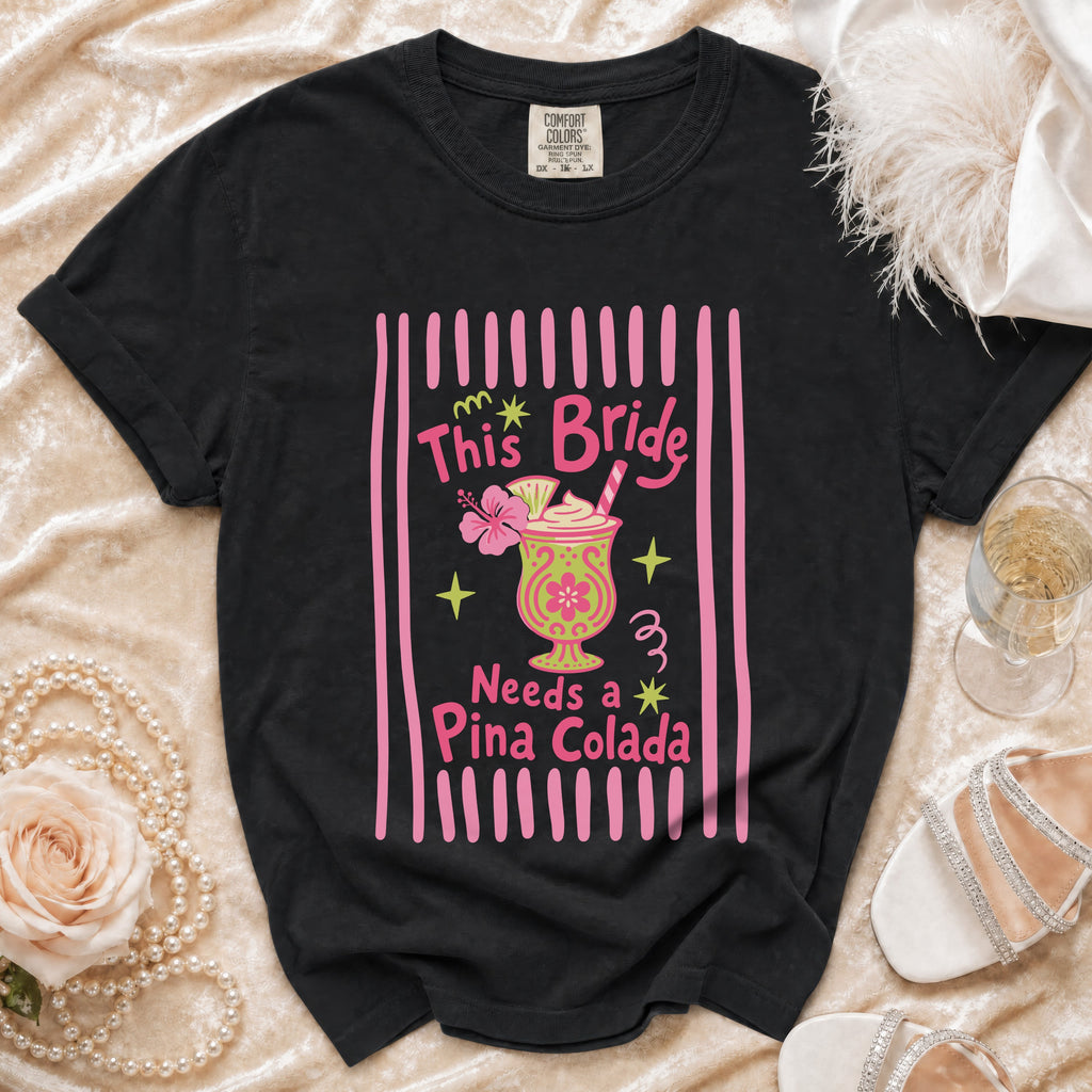 Black t-shirt with "This Bride Needs a Piña Colada" graphic and cocktail.
