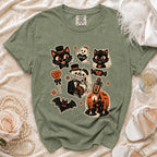 Green t-shirt with Halloween graphic featuring cats, skeletons, ghost, and haunted house.