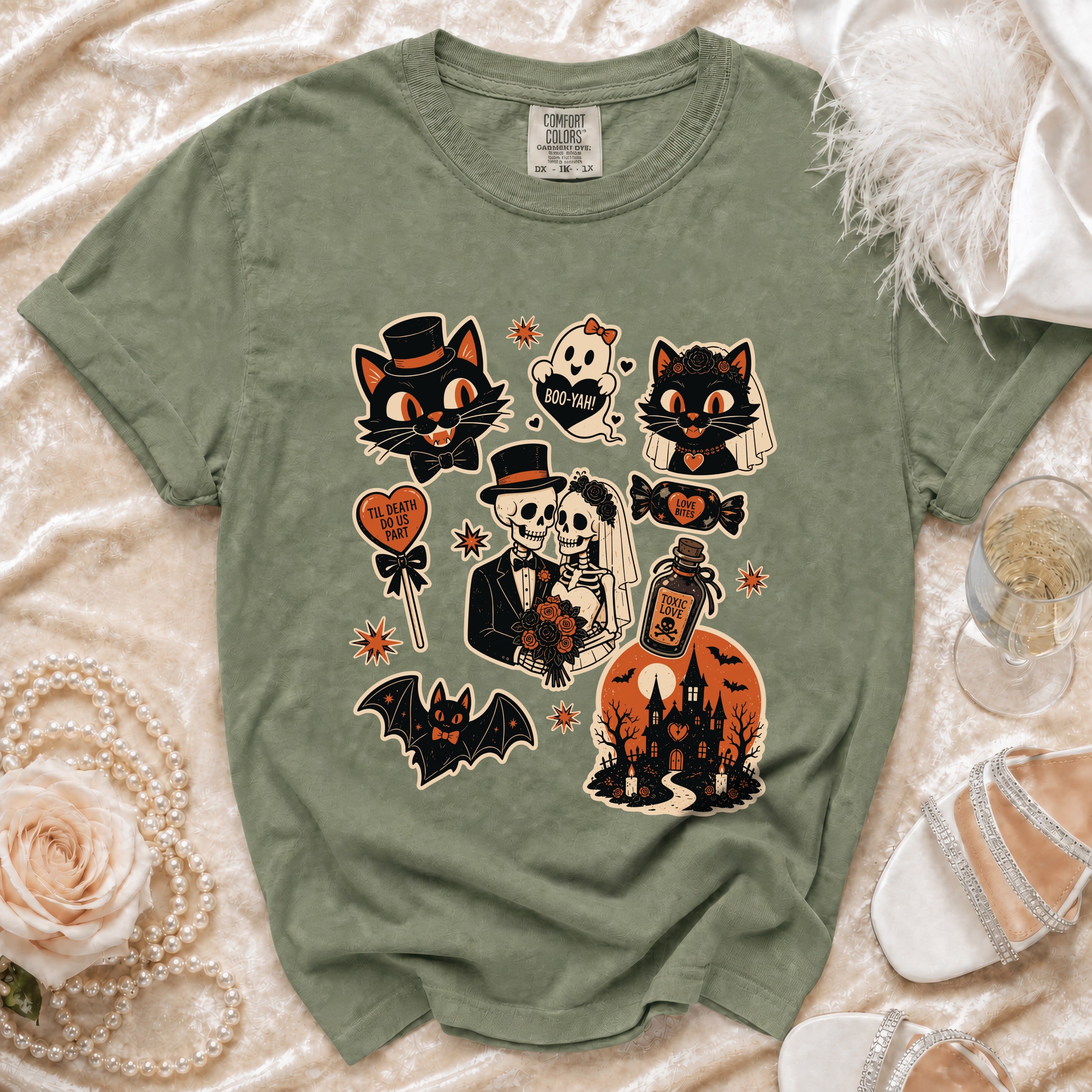 Green t-shirt with Halloween graphic featuring cats, skeletons, ghost, and haunted house.