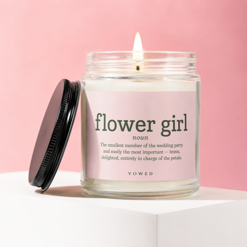 Lit candle in jar labeled "flower girl noun" with wedding party description.