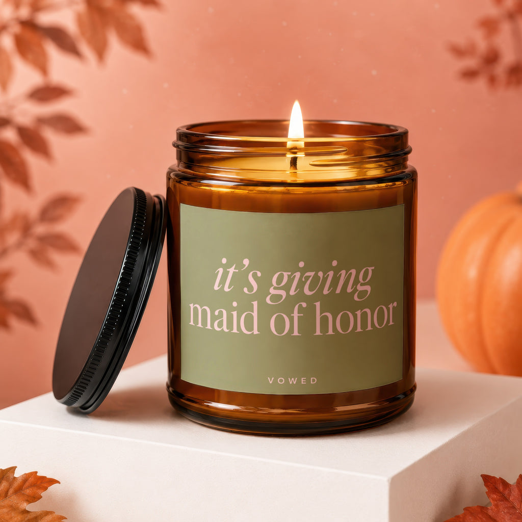 Amber candle with lit wick, "it's giving maid of honor" text.
