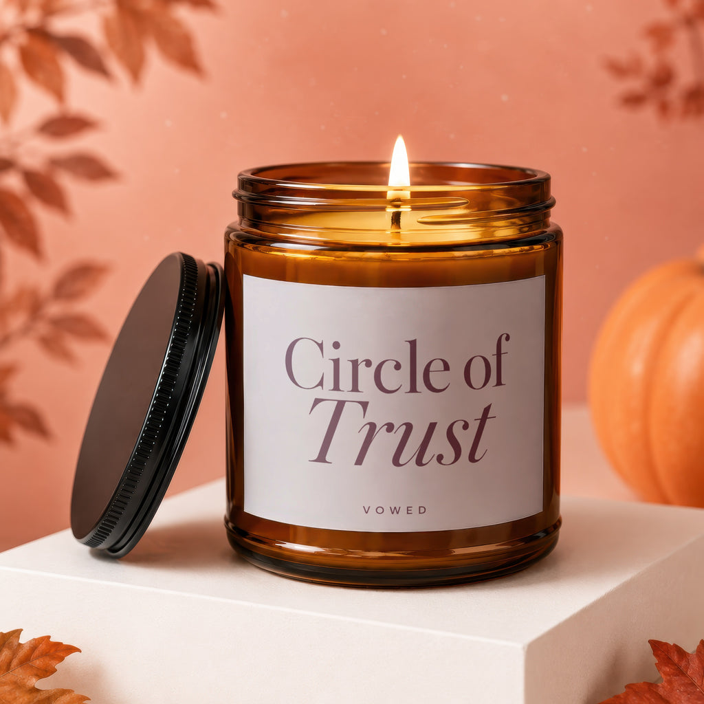 Lit amber glass candle with white label reading "Circle of Trust Vowed".