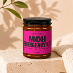 Amber jar with black lid labeled "MOH Emergency Kit" including "Safety Pins, Snacks, This Candle".