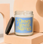 Glass candle with blue label that reads "Chosen, Loved, Married VOWED".