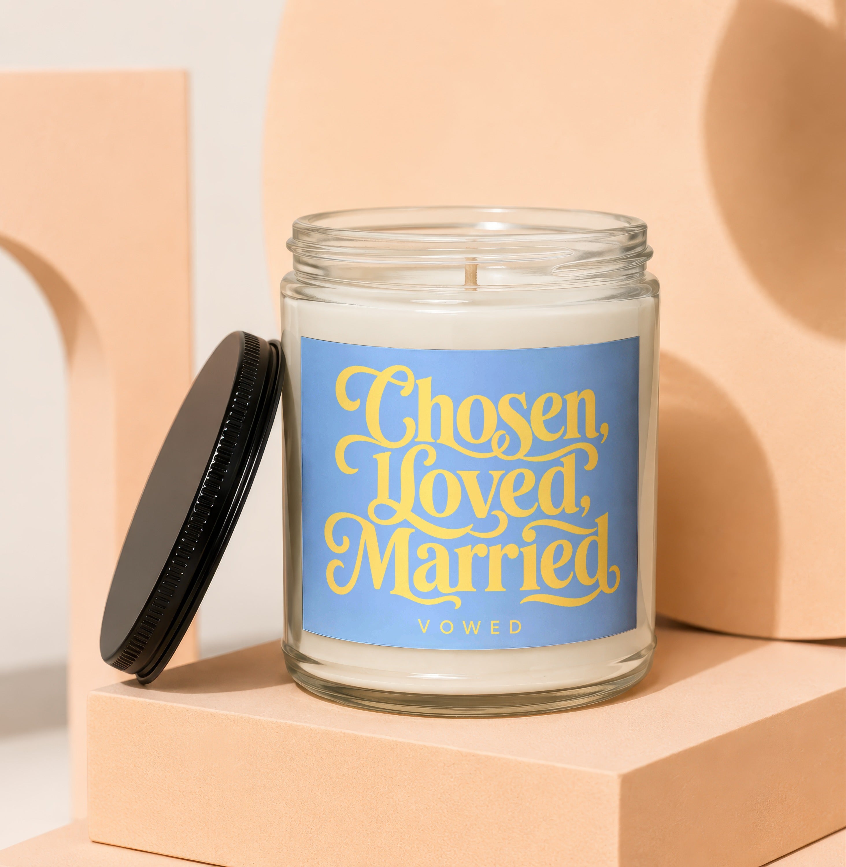 Glass candle with blue label that reads "Chosen, Loved, Married VOWED".