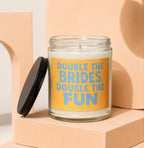 Glass candle with orange label reading "DOUBLE THE BRIDES, DOUBLE THE FUN".