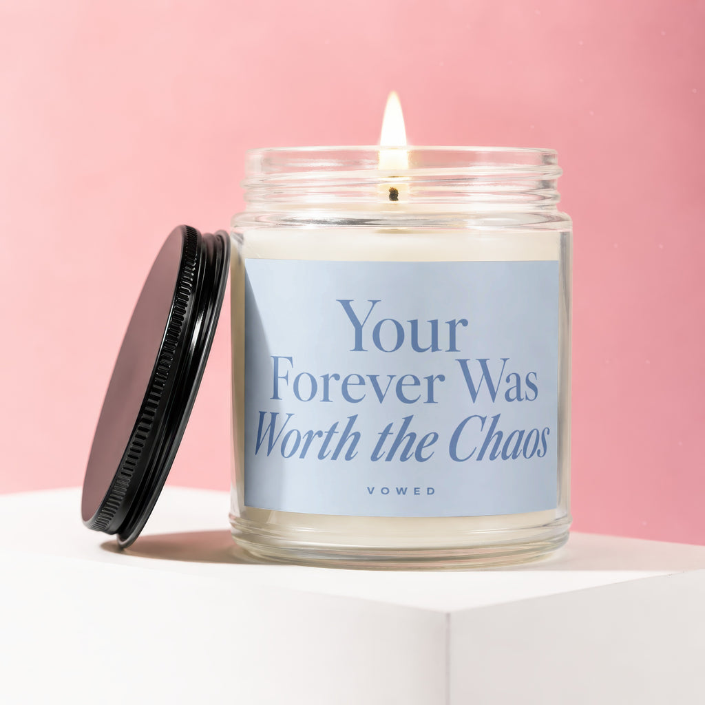 Glass candle with lid off, lit flame, blue label with text "Your Forever Was Worth the Chaos".