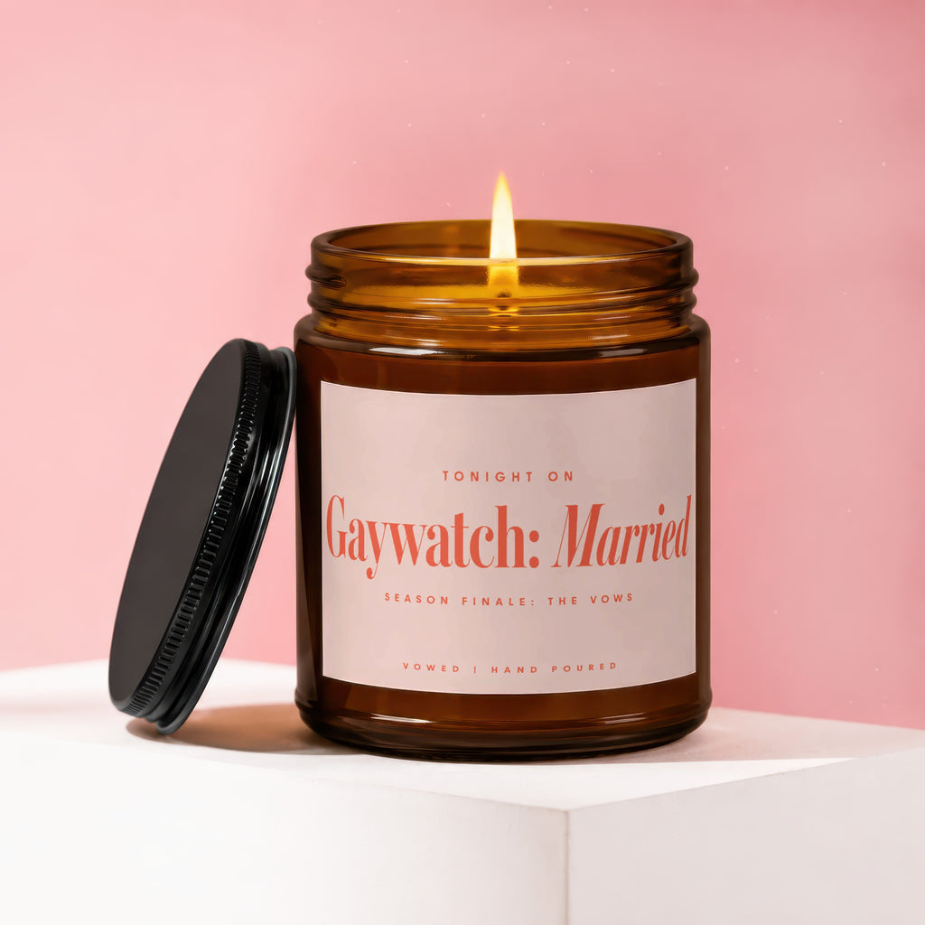 Brown glass candle with lit flame and black lid. Label reads "Gaywatch: Married".