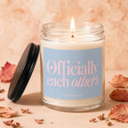 A lit candle in a jar with a blue label that says "Officially each other's vowed".