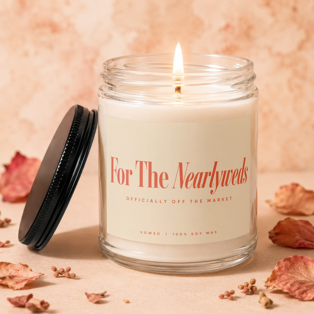Glass jar candle with lit wick, "For The Newlyweds" text, and black lid.