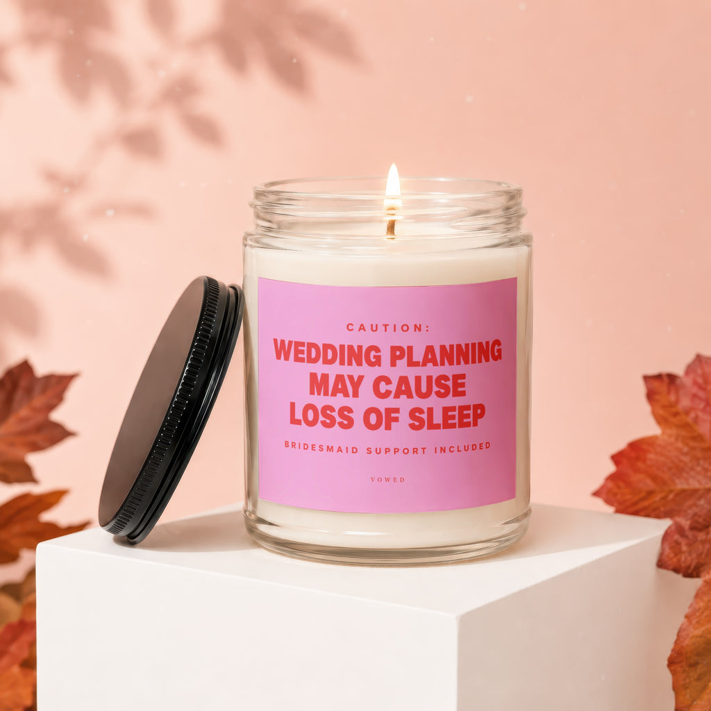 Candle with pink label reading "CAUTION: WEDDING PLANNING MAY CAUSE LOSS OF SLEEP".