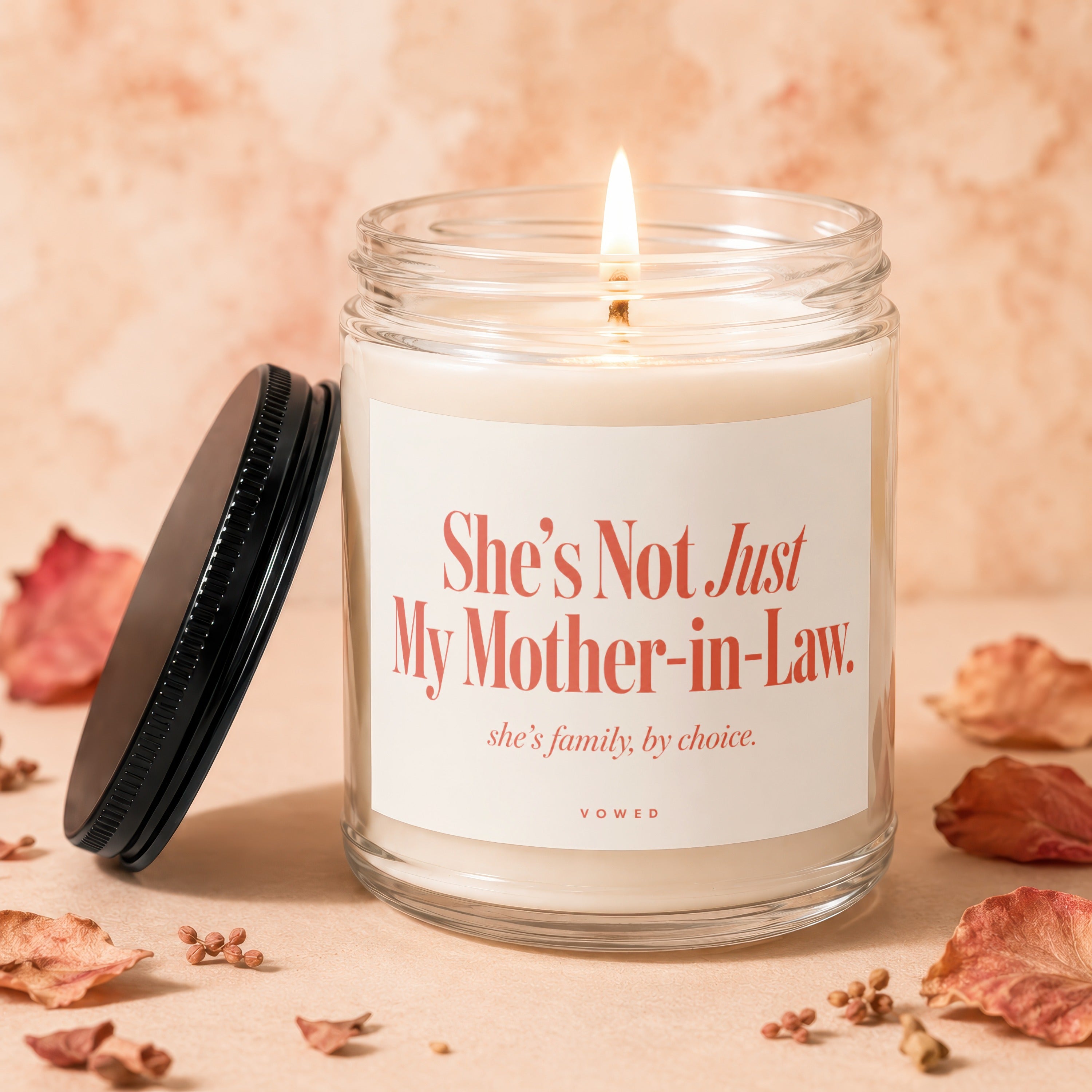 Glass candle with lit wick, text: "She's Not Just My Mother-in-Law. she's family, by choice."