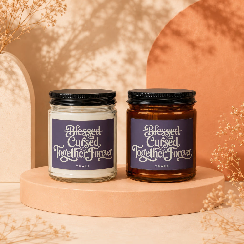 Two candles, one white and one amber, with "Blessed Cursed Together Forever" labels.