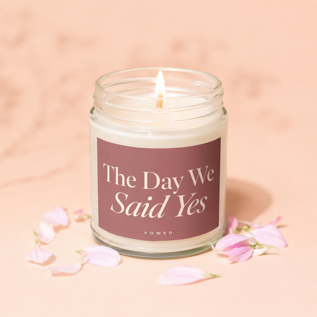 Glass jar candle with lit wick, labeled "The Day We Said Yes."