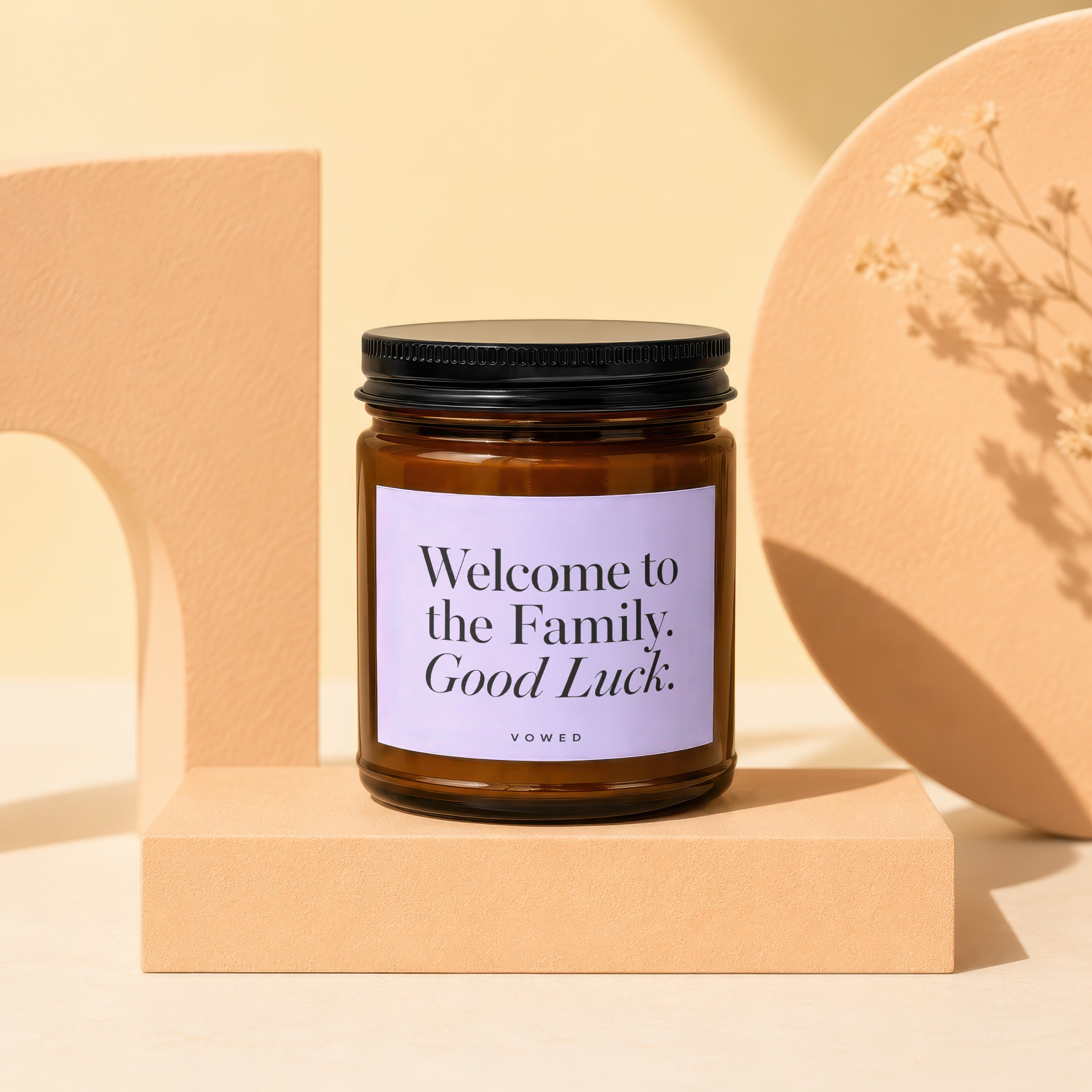 Amber candle with a white label saying "Welcome to the Family. Good Luck."