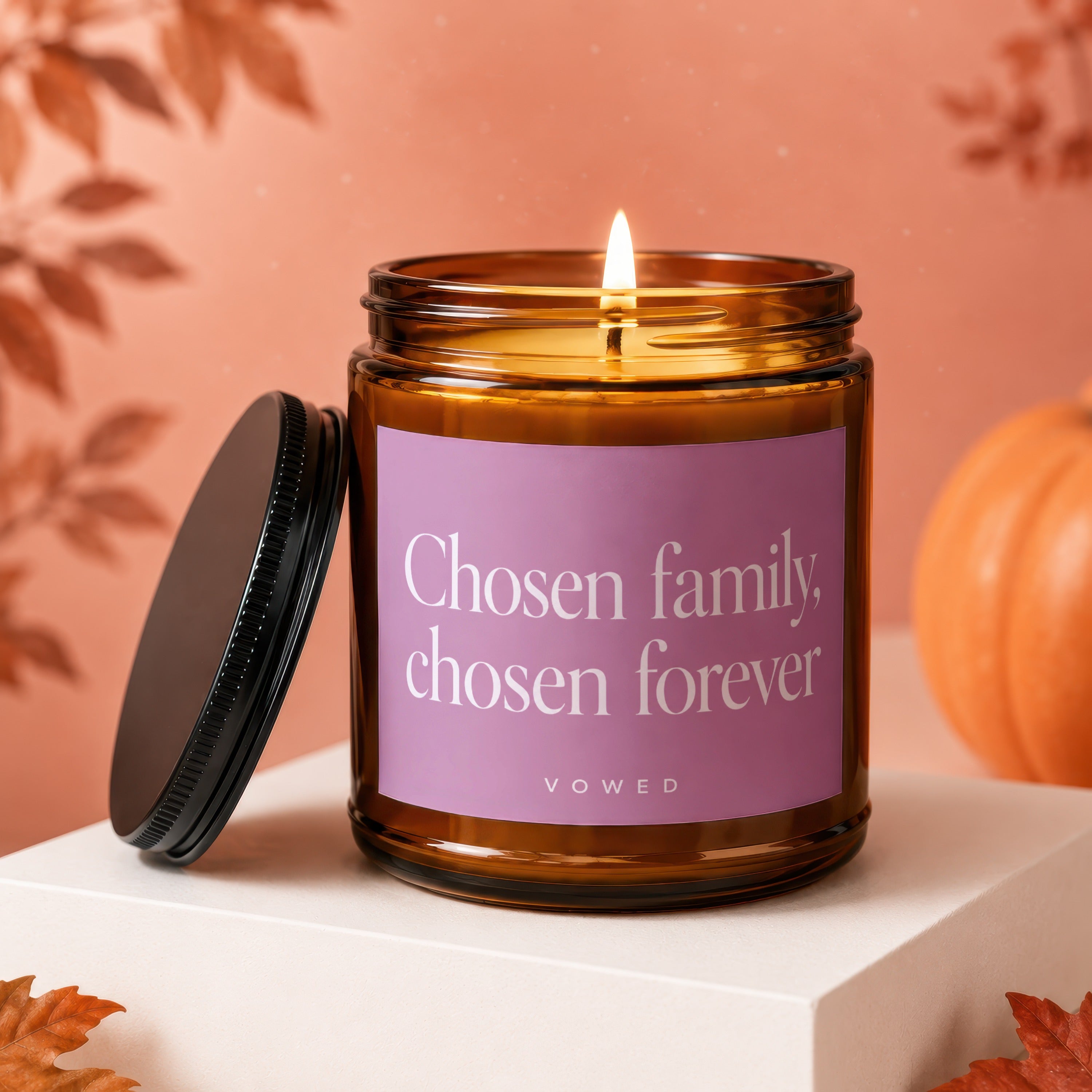 Glass candle with lit wick, reads "Chosen family, chosen forever" and "vowed".