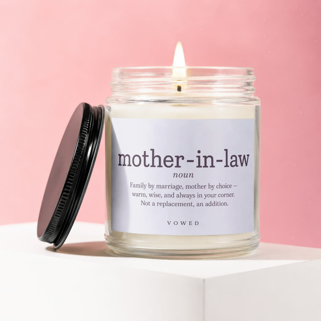 Glass candle with a lit wick and a label defining "mother-in-law".