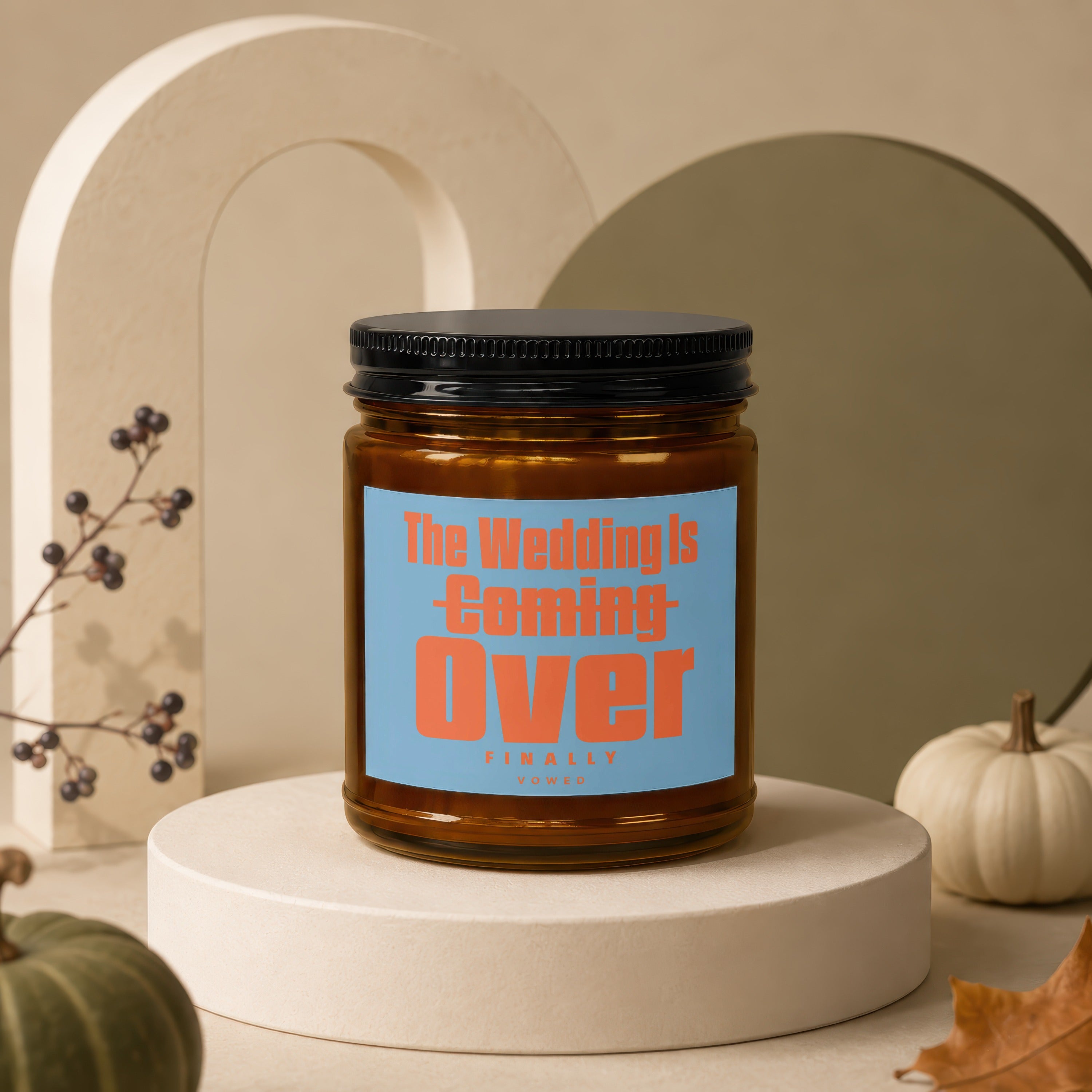 Amber candle with black lid, blue label reads "The Wedding Is Coming Over FINALLY VOWED".