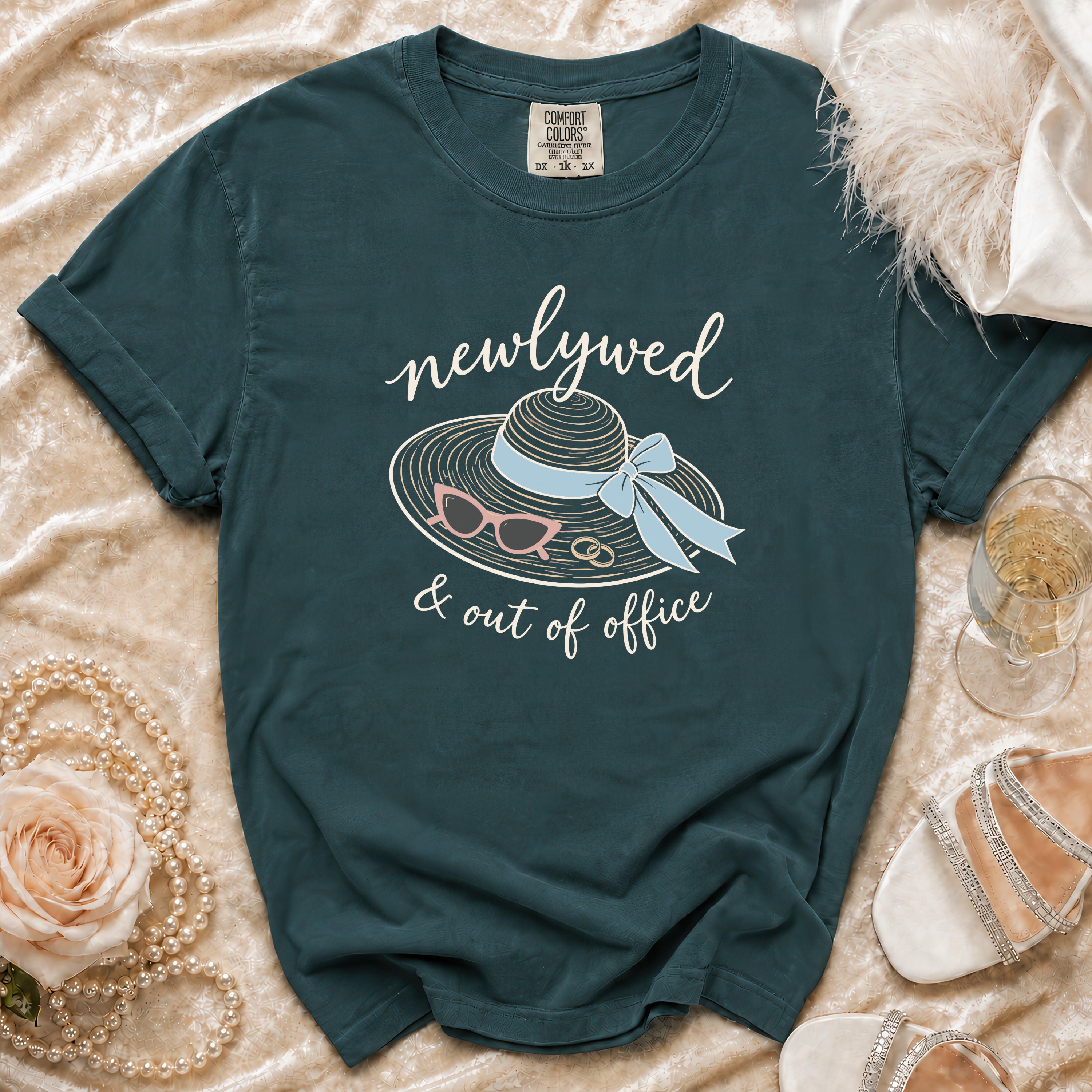 Newlywed & out of office graphic tee with a straw hat, sunglasses, and rings.