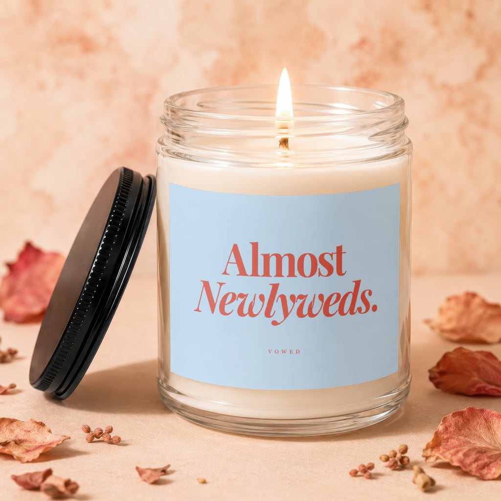 Glass jar candle with lit flame, "Almost Newlyweds. VOWED" label.