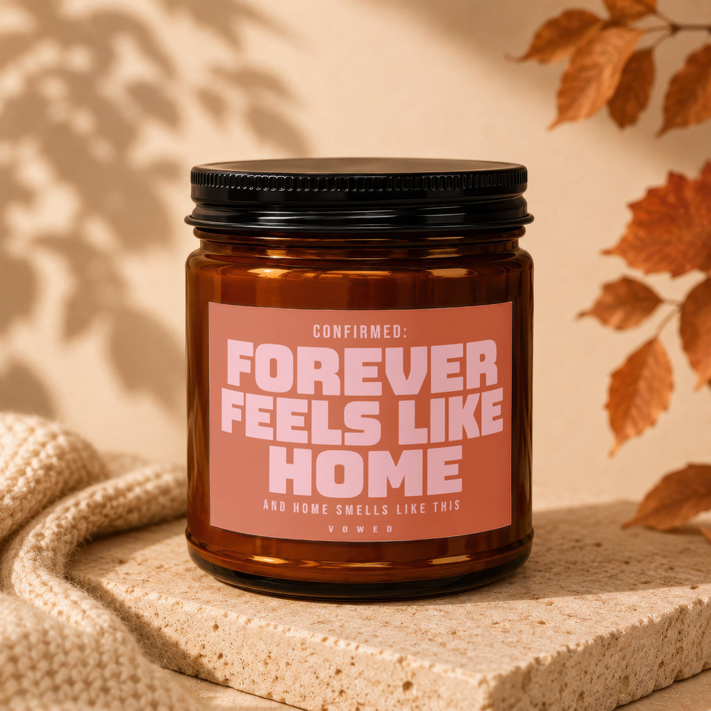 Amber candle with label reading "CONFIRMED: FOREVER FEELS LIKE HOME".
