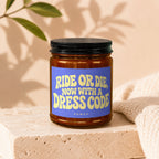Amber jar candle with blue label stating "RIDE OR DIE, NOW WITH A DRESS CODE", text "vowed" below.