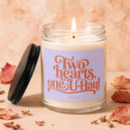 Candle with lit wick, lilac label reading "Two hearts, one U-Haul" and "VOWED".