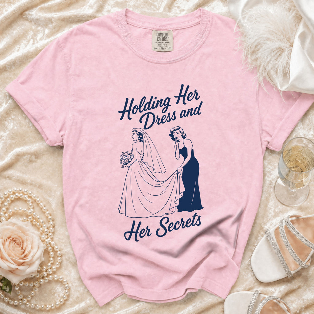 Pink t-shirt with navy graphic of two women "Holding Her Dress and Her Secrets".