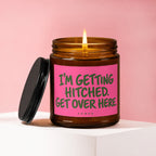 Amber jar candle with a pink label reading "I'M GETTING HITCHED. GET OVER HERE."