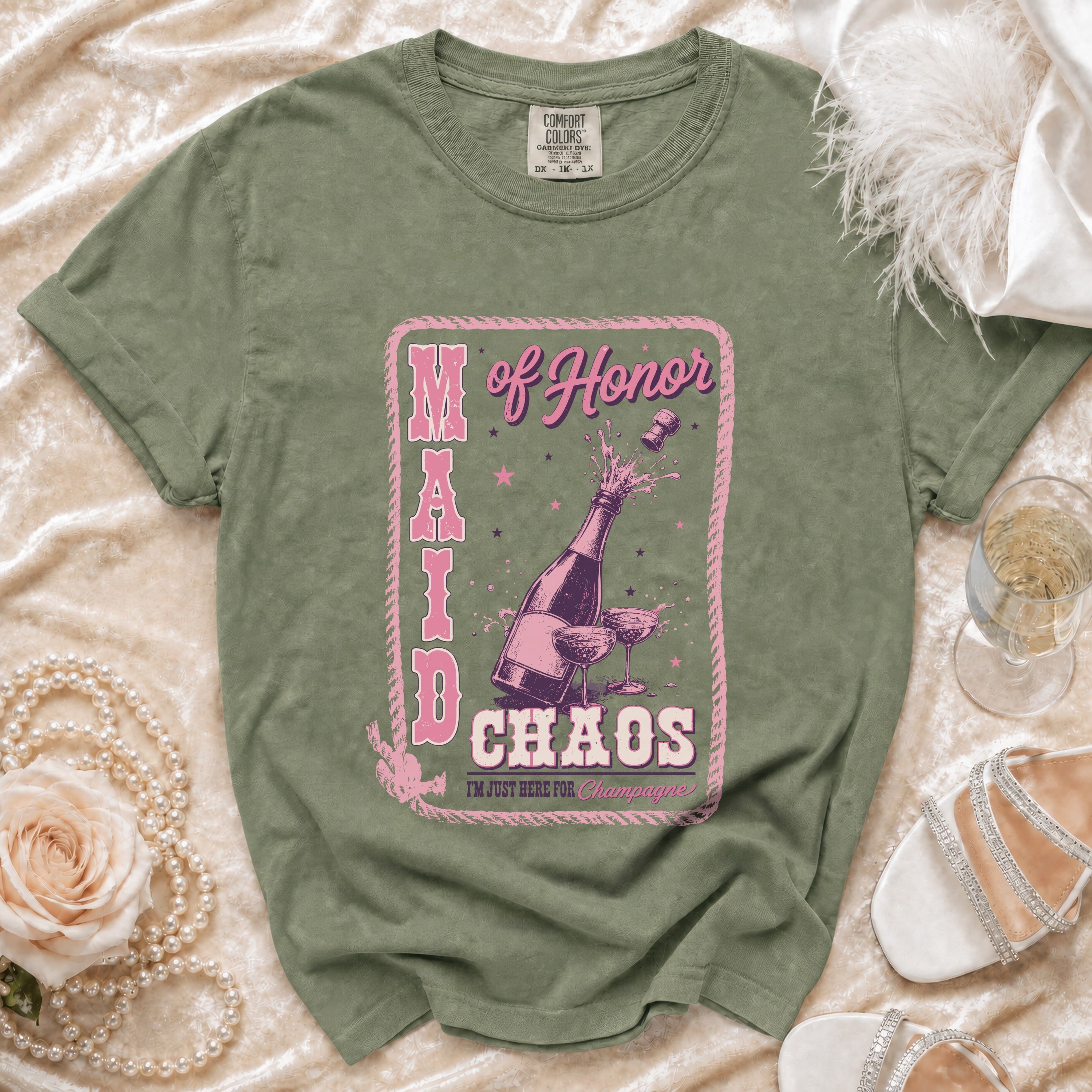 Green t-shirt with "Maid of Honor Chaos" text and champagne illustration.