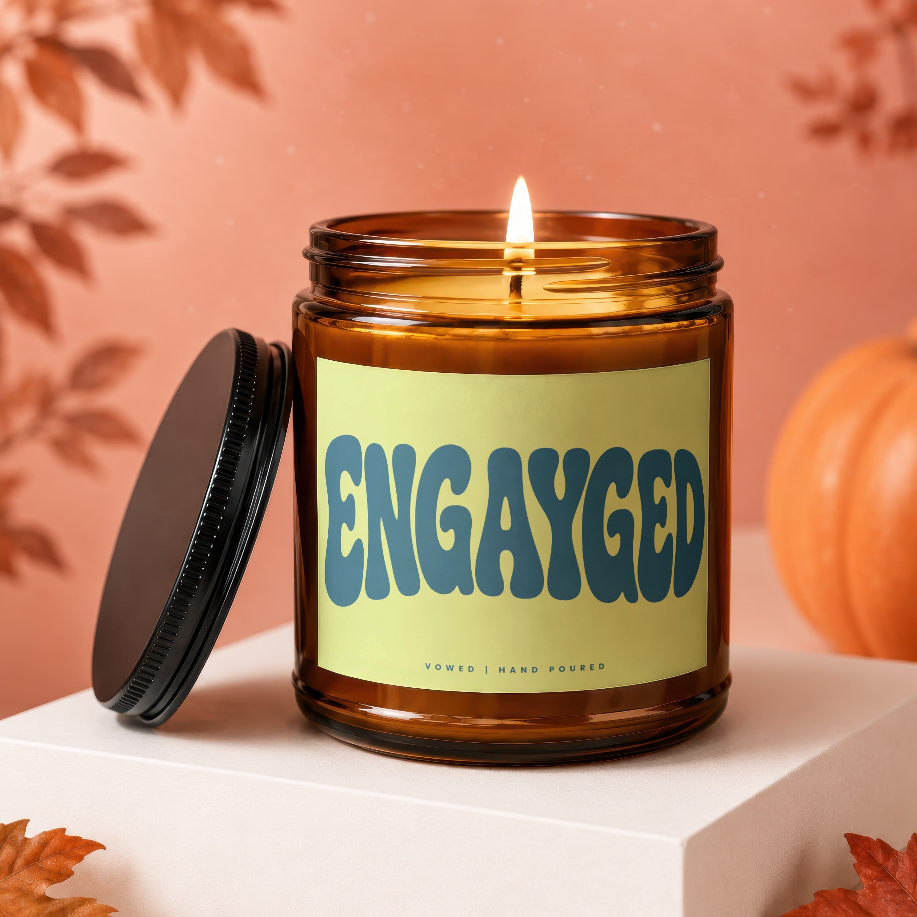 Amber candle with a lit wick and "ENGAYGED" text on a yellow label.