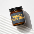 Amber glass candle with dark label reading "Appointed: Moonlit Maid of Honor"