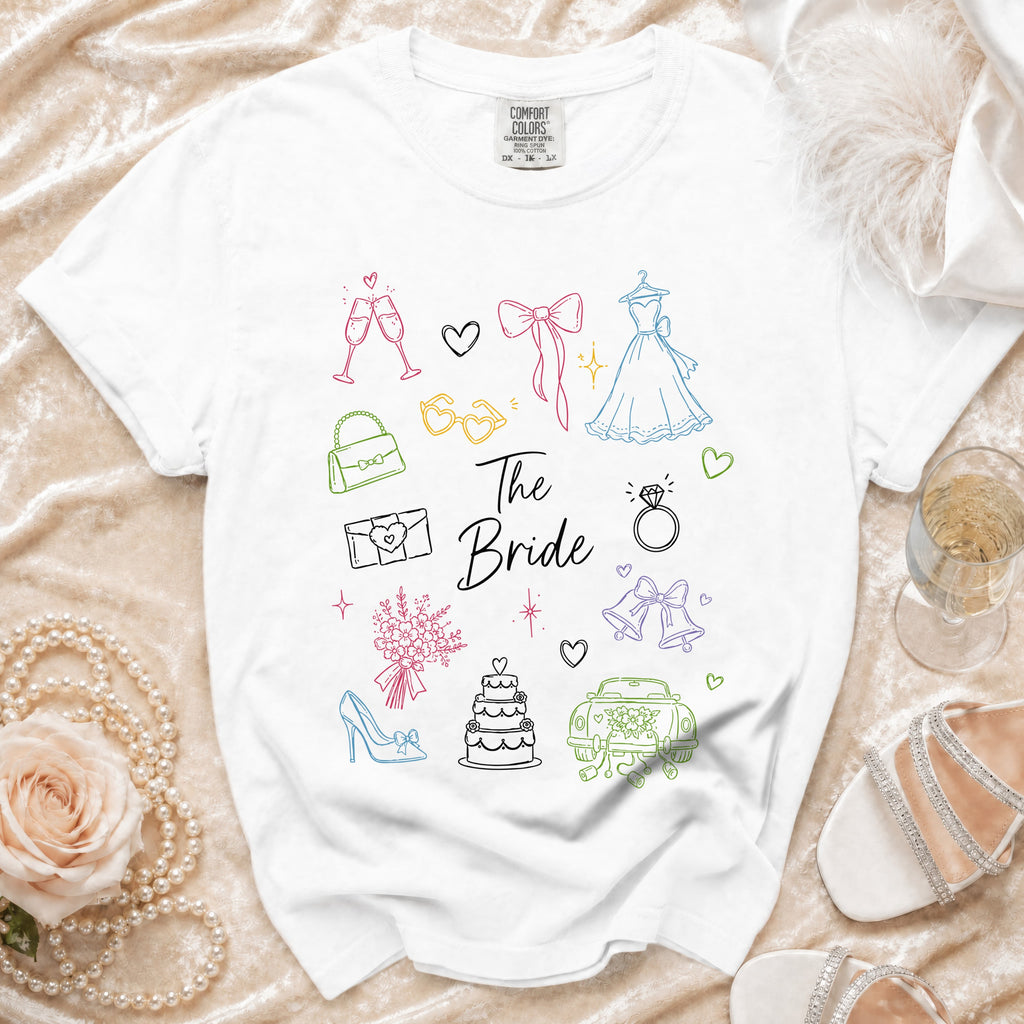 White t-shirt with colorful line drawings of wedding elements and text "The Bride".