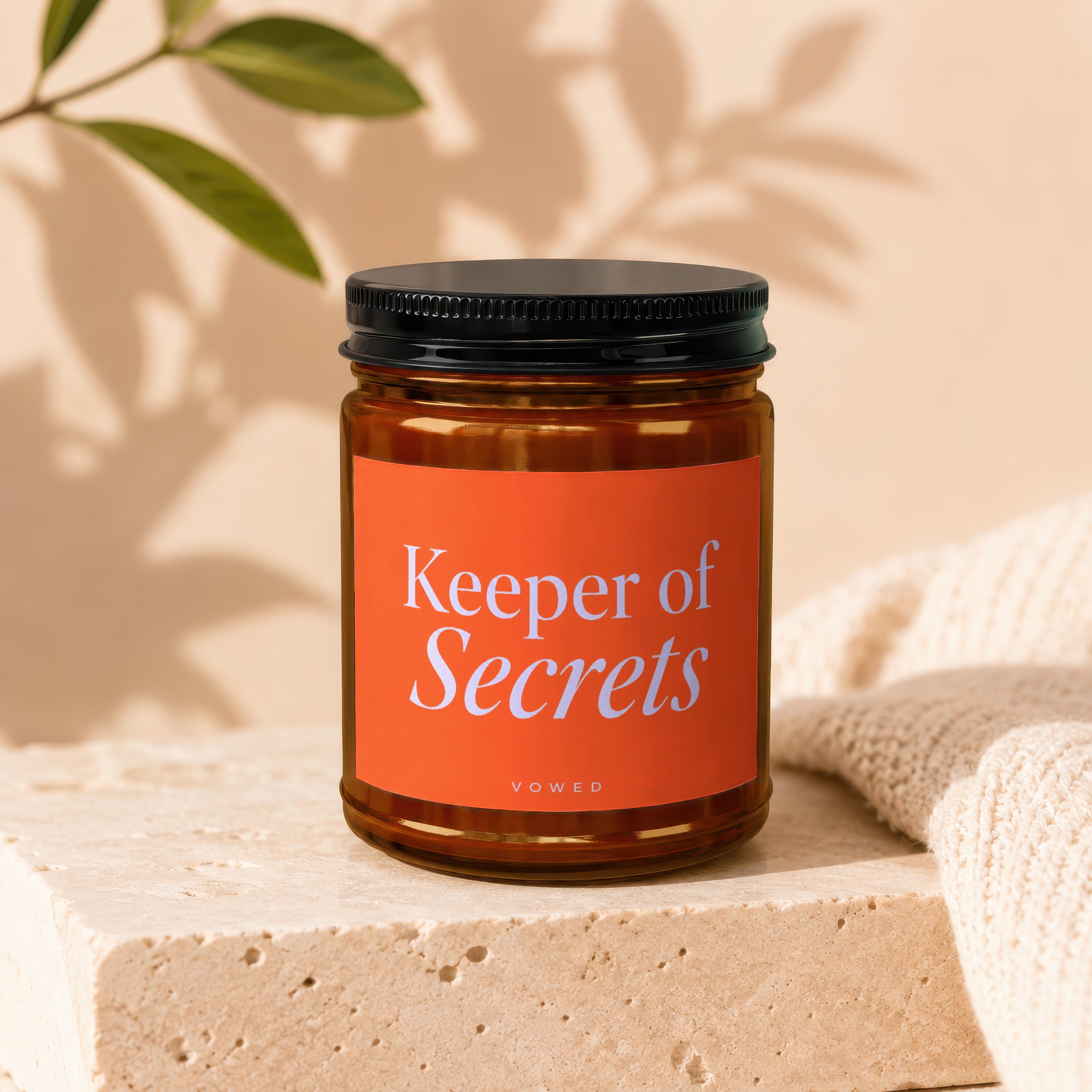 Amber jar candle with orange label reading "Keeper of Secrets" and "VOWED"