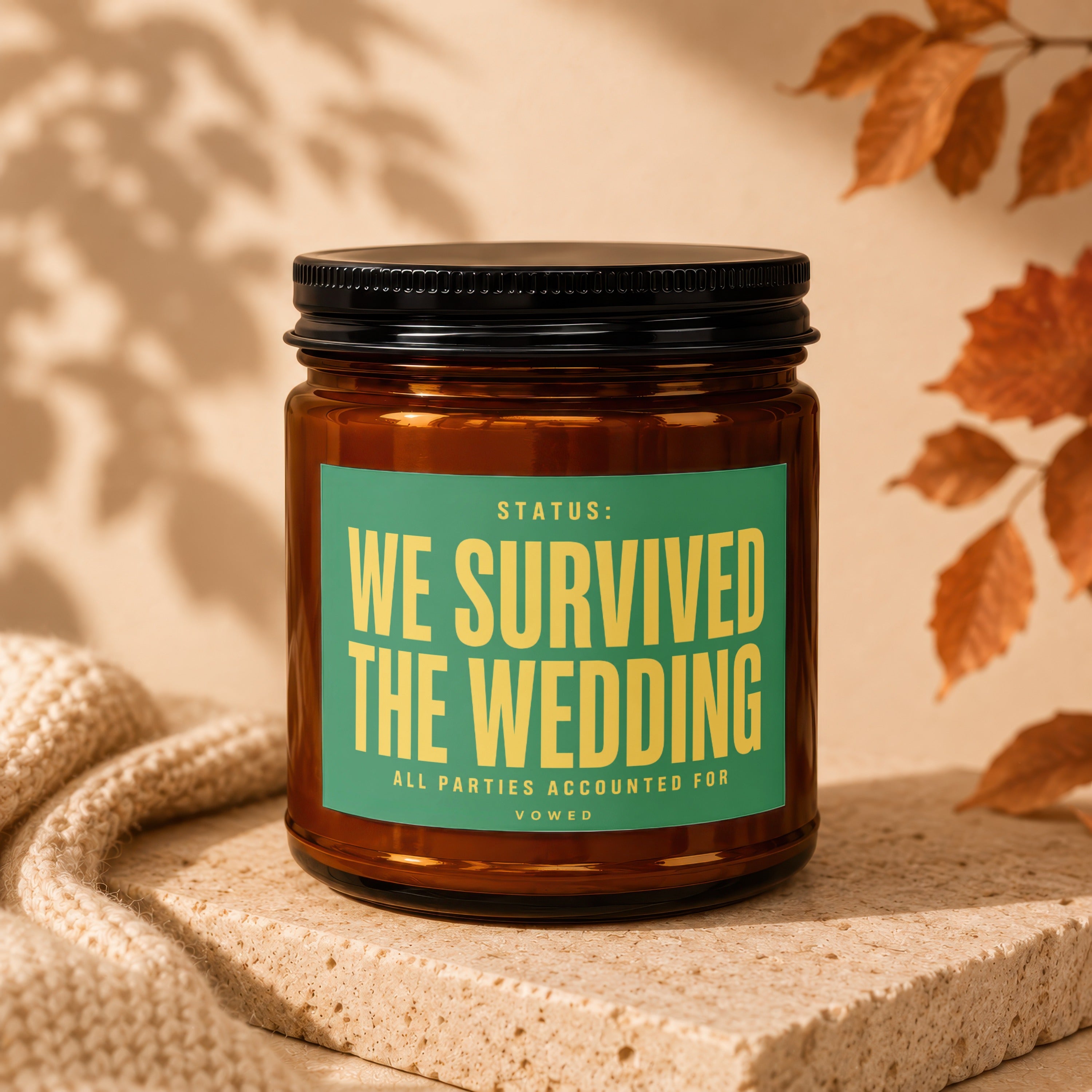 Amber jar candle with green label that reads "Status: We survived the wedding."