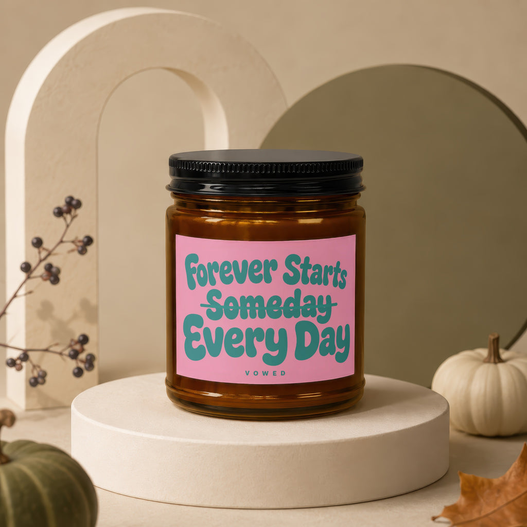 Amber candle with pink label reading "Forever Starts Someday Every Day"