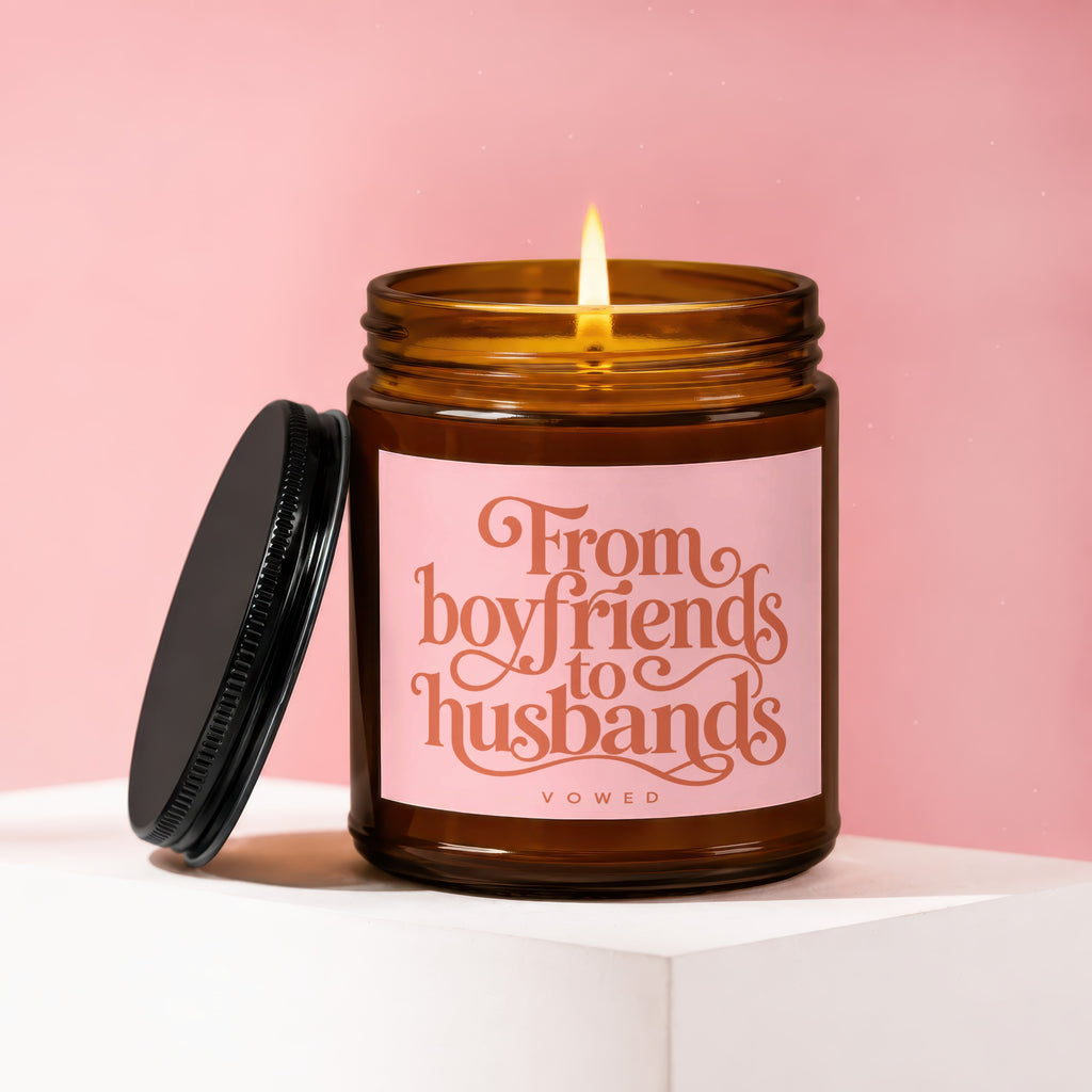 Candle with lit flame and pink label reading "From boyfriends to husbands VOWED."