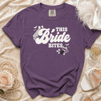 Purple t-shirt with "This Bride Bites" graphic, featuring spooky elements.