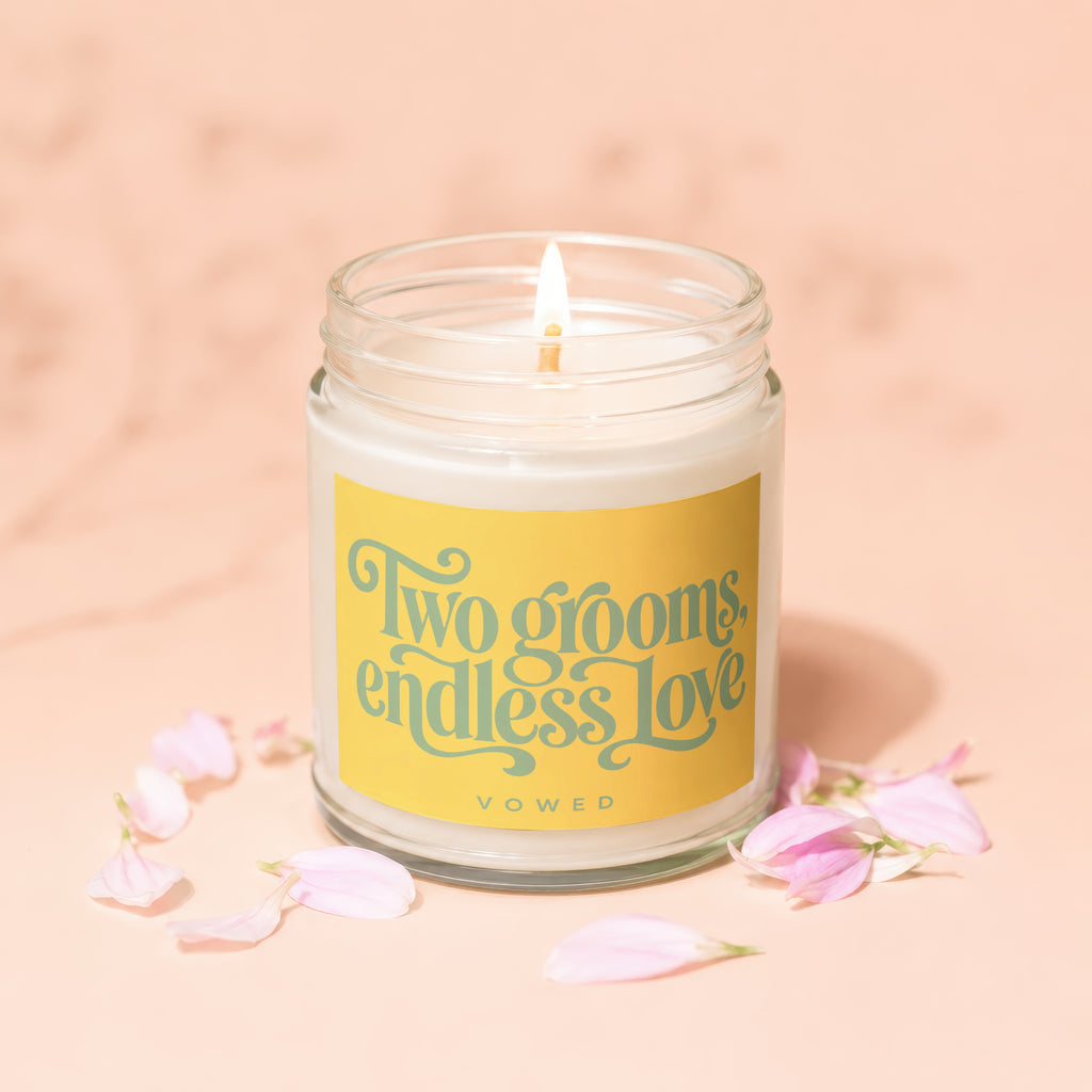 Candle with lit wick and yellow label reading "Two grooms, endless love"