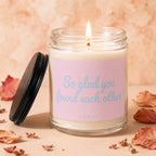 Burning scented candle in glass jar with pink label that reads "So glad you found each other".
