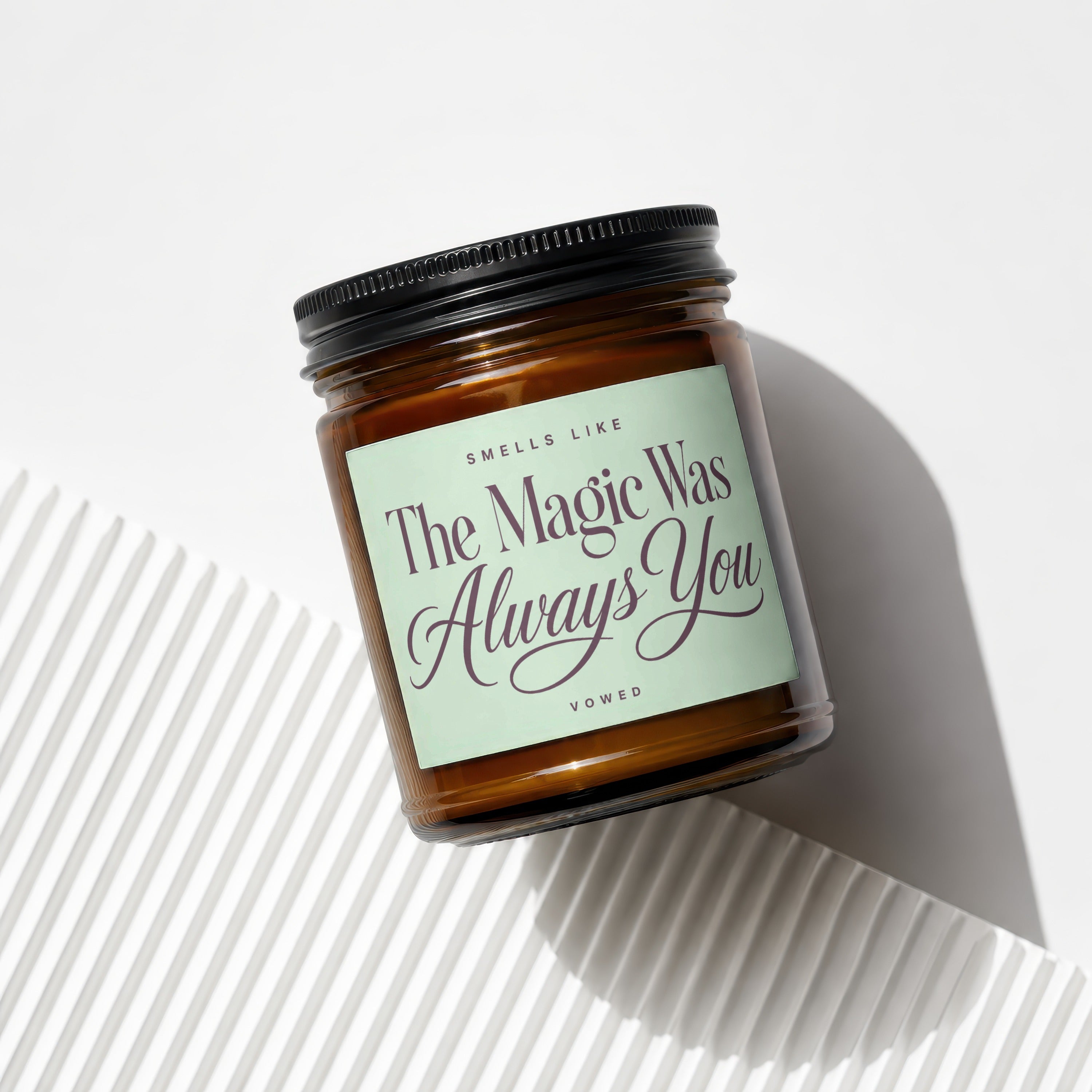 Amber glass candle with black lid, label reads "Smells Like The Magic Was Always You".