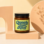 Queerly Ever After Vowed candle in amber glass jar with black lid.