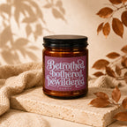 Brown glass candle with black lid and label reading "Betrothed, bothered, bewildered," VOWED.