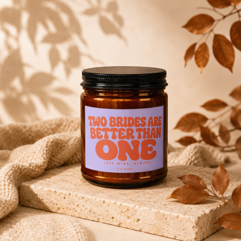 Amber candle with a lavender label that reads "TWO BRIDES ARE BETTER THAN ONE LOVE WINS, ALWAYS VOWED".