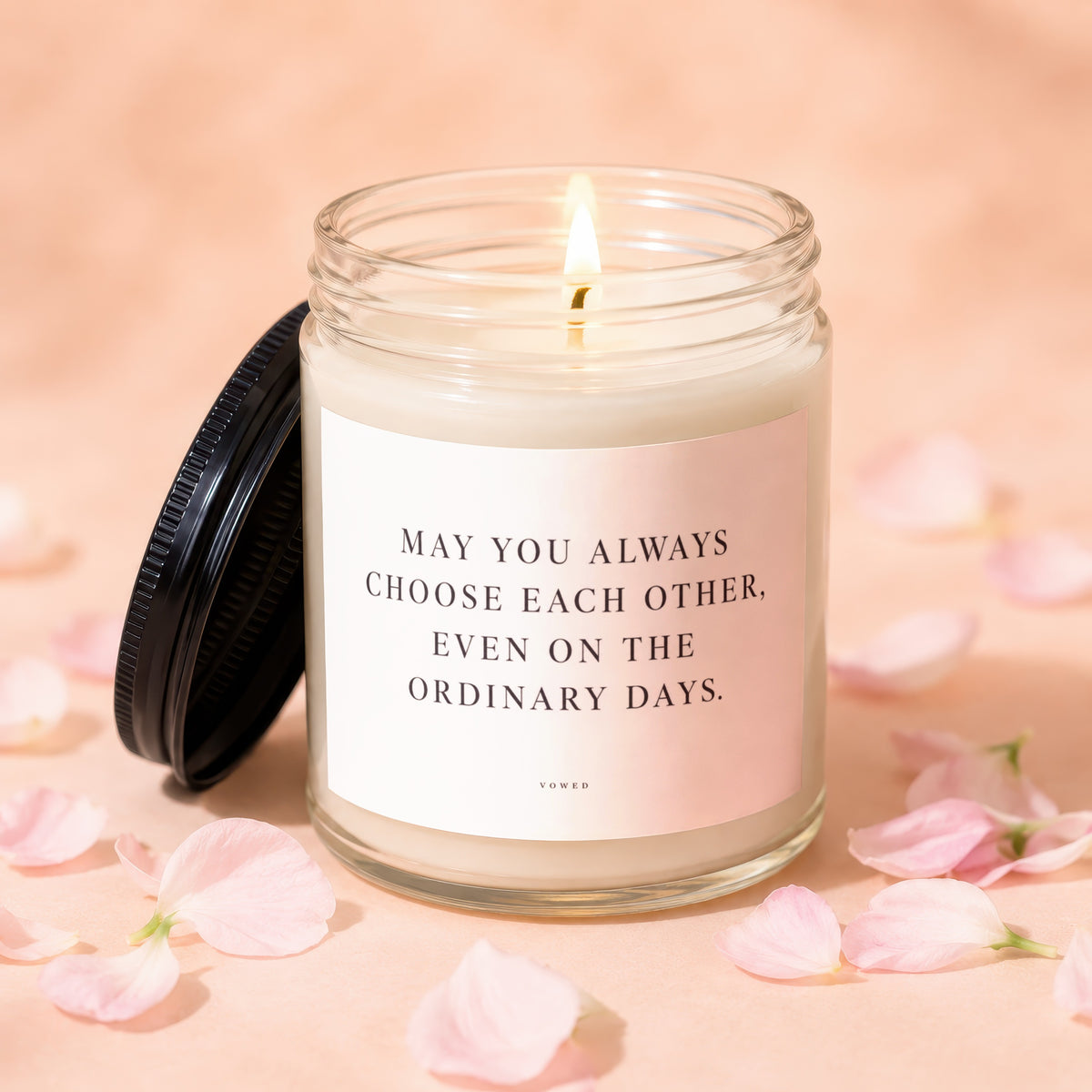 Glass candle with lit wick and a label reading "May you always choose each other, even on the ordinary days."