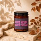 Amber jar candle with "Love Never Feared the Dark" on label.