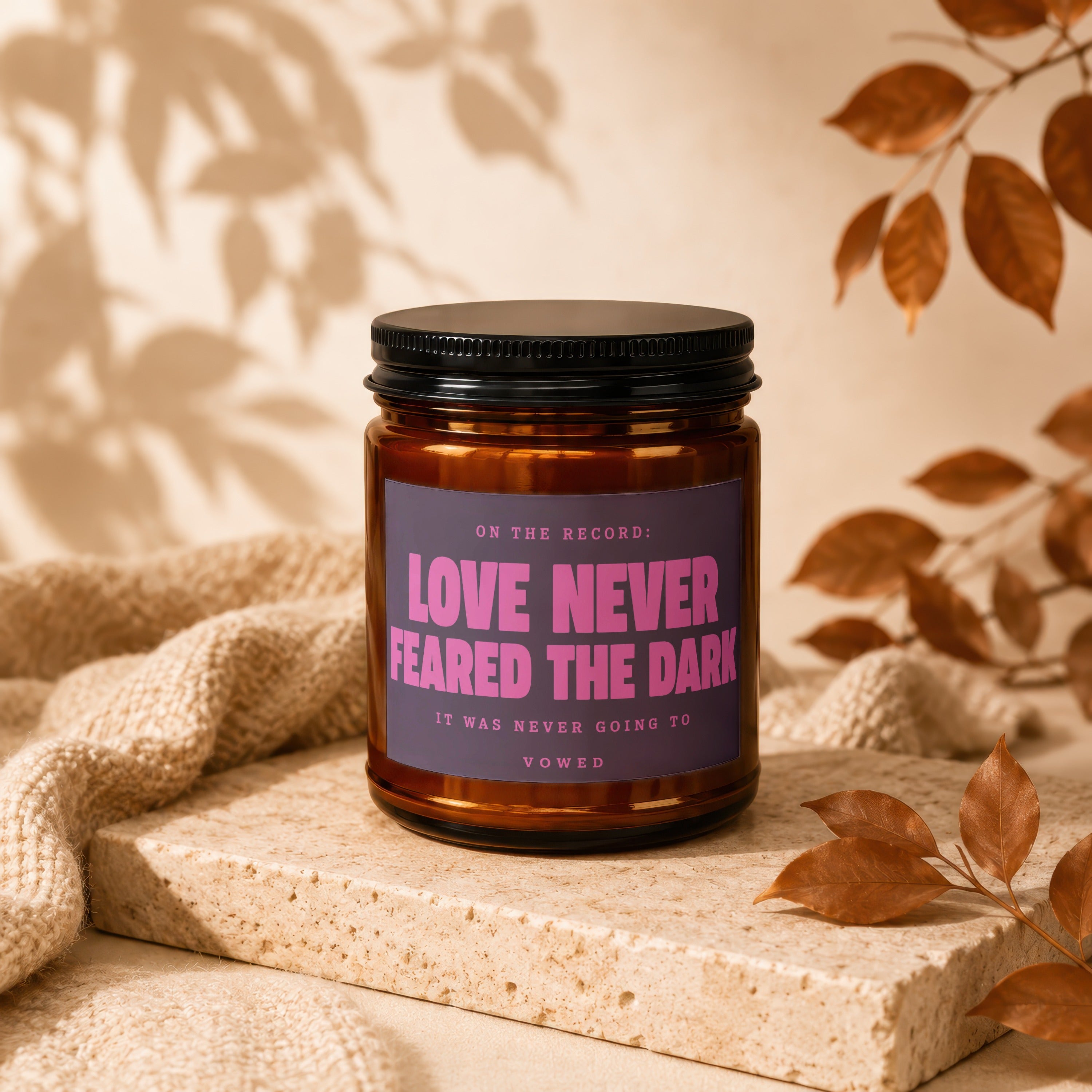 Amber jar candle with "Love Never Feared the Dark" on label.