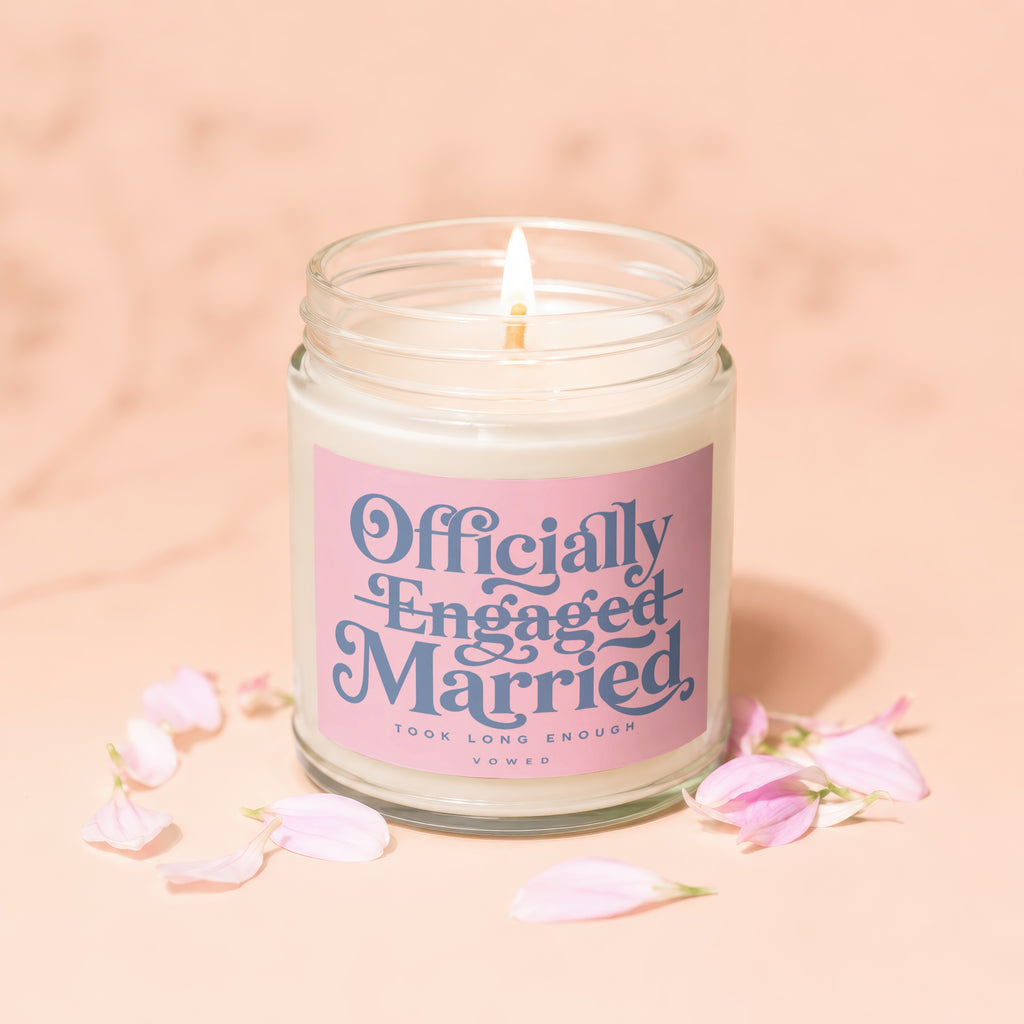 Candle with "Officially Engaged Married" text and pink petals scattered around.