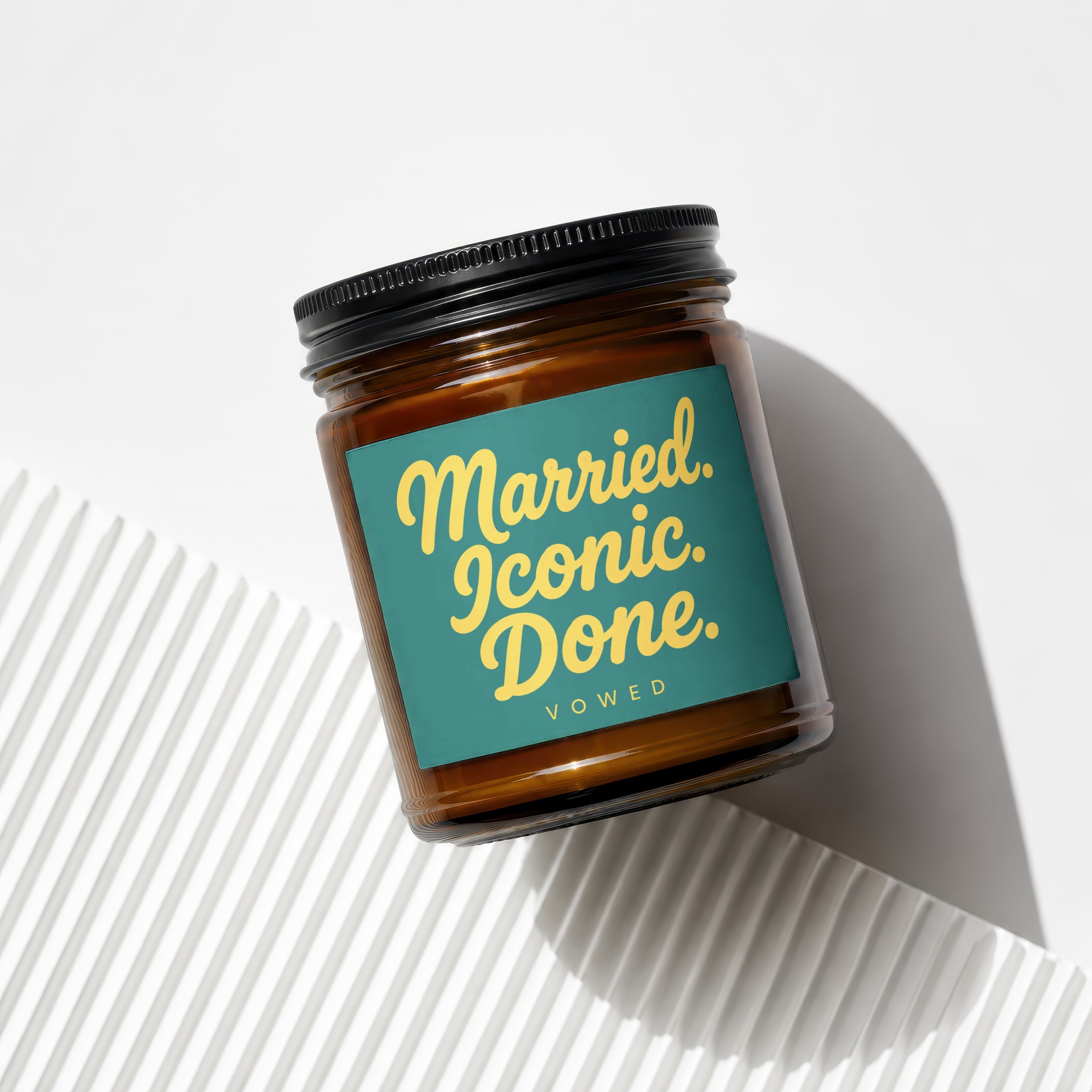 Amber jar candle with teal label reading "Married. Iconic. Done. VOWED."